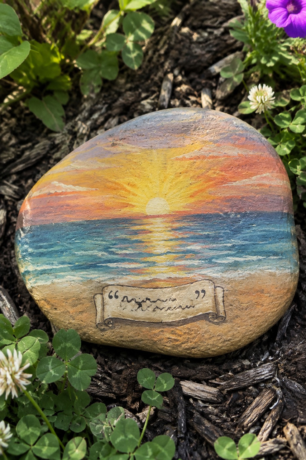 Painted rock with vibrant sunset over ocean, sandy beach, and mom banner.