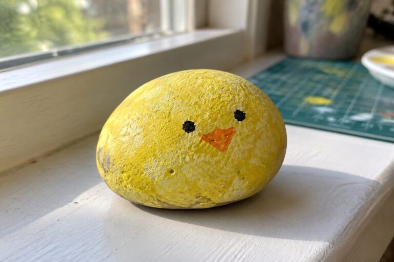 16 Preschool Rock Painting Projects With Sponge-Painted Designs Yellow painted rock chick with orange beak on sunny white windowsill
