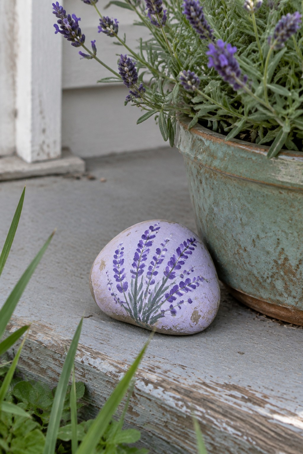 Painted rock with lavender flowers beside potted plant on wooden steps
