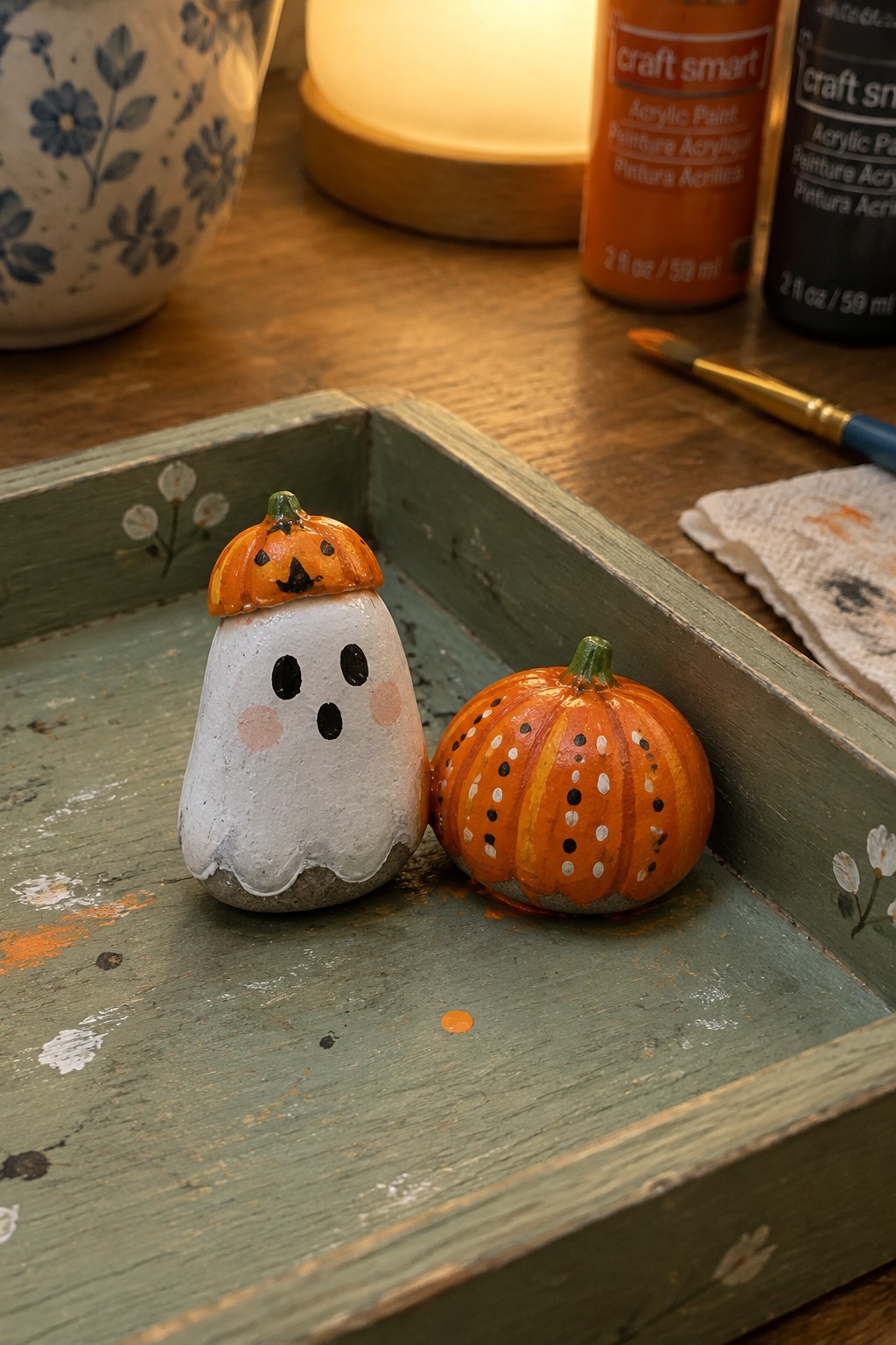 Ghost rock with pumpkin hat beside dotted orange pumpkin on green tray