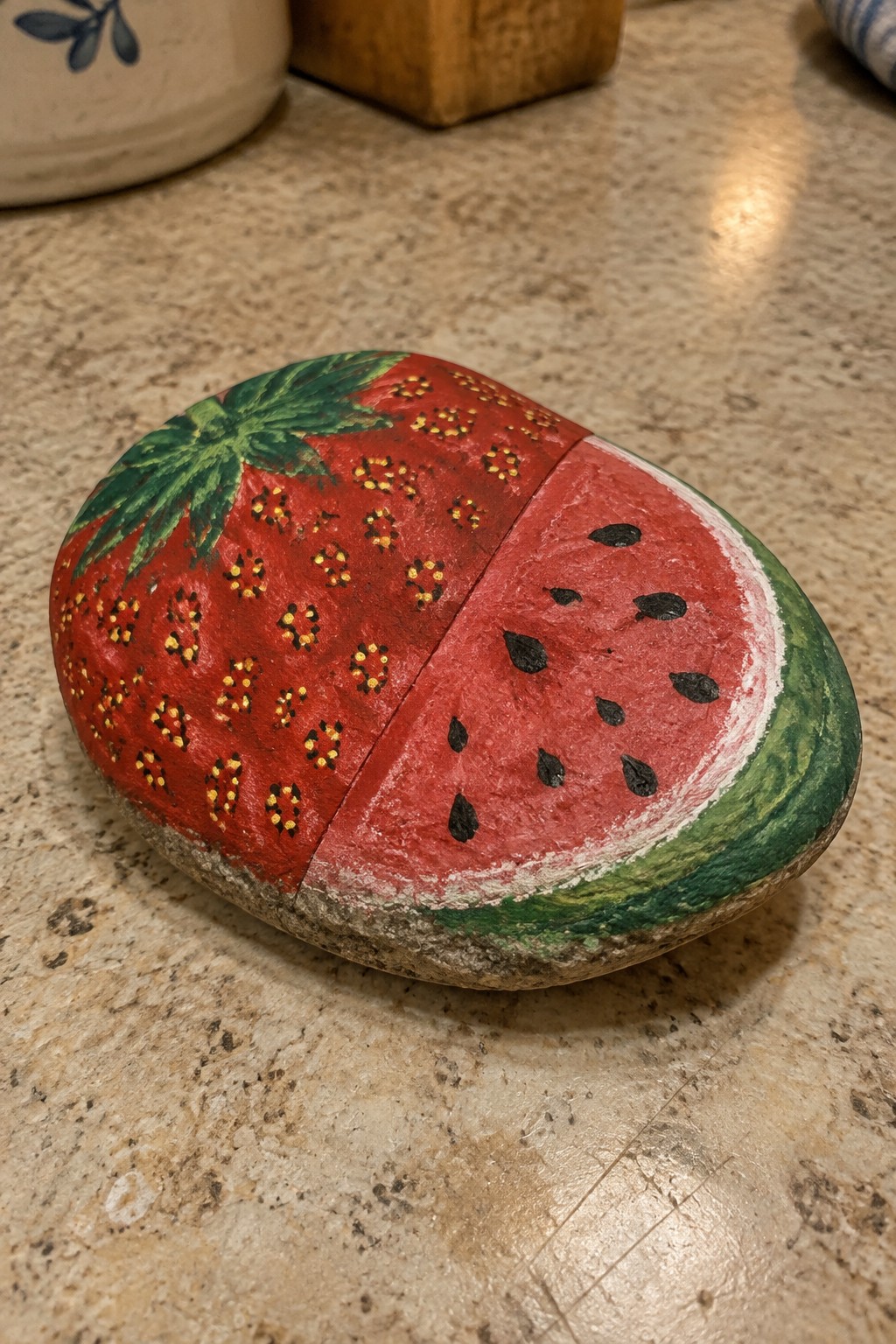 Painted rock split as strawberry and watermelon on granite countertop