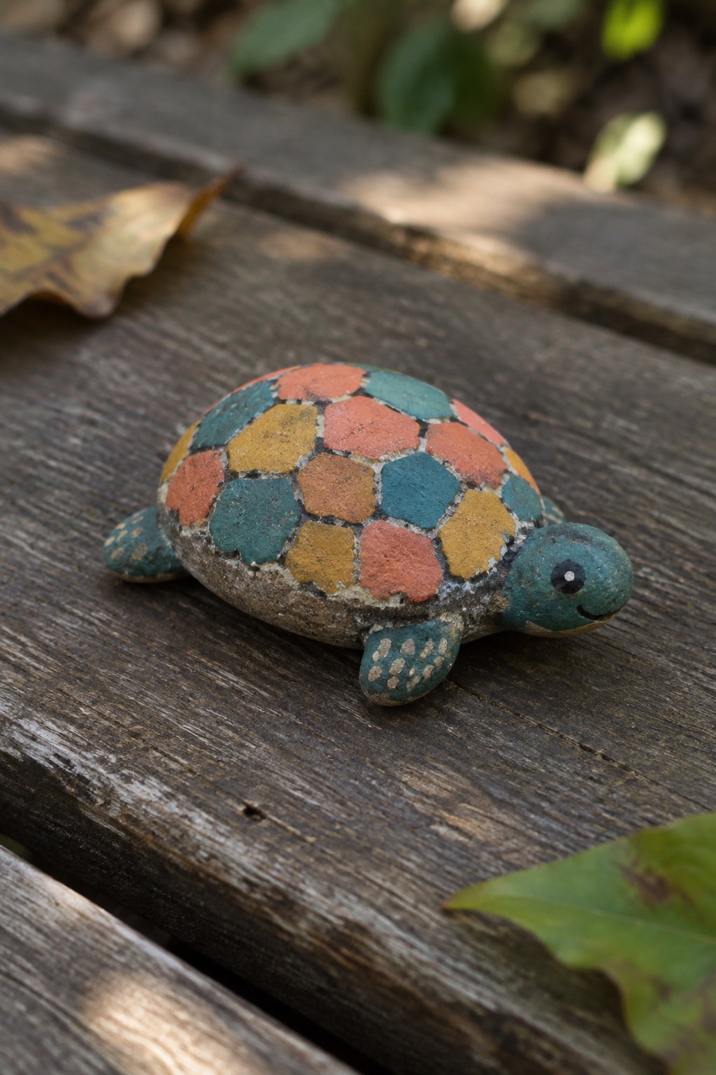 Colorful painted turtle figurine with mosaic orange teal shell on weathered wood