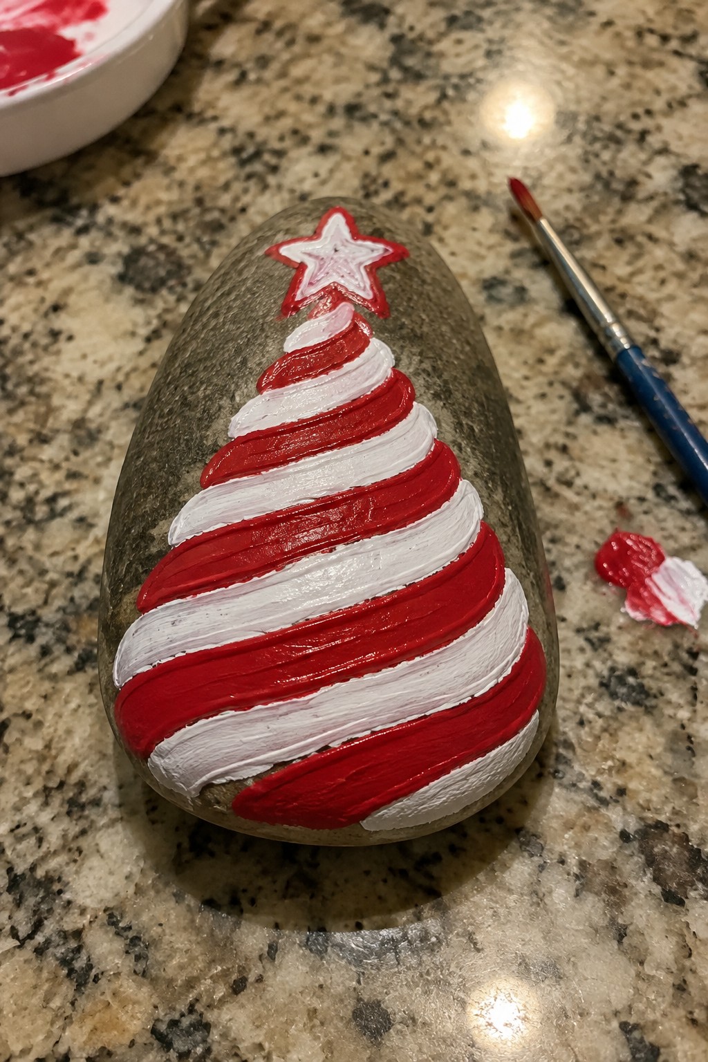 Rock painted with red and white striped Christmas tree and star on top